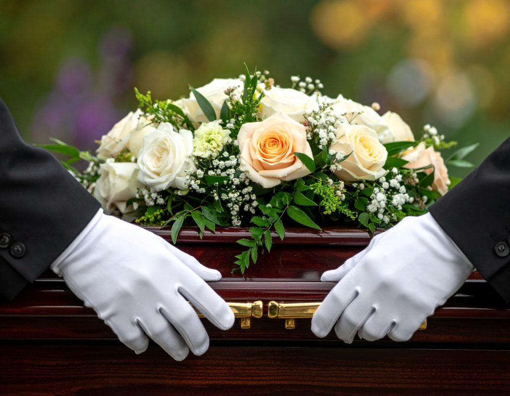 Gros plan sur les mains gantées de blanc des porteurs tenant les poignées en laiton d'un cercueil, symbolisant le respect et le soin