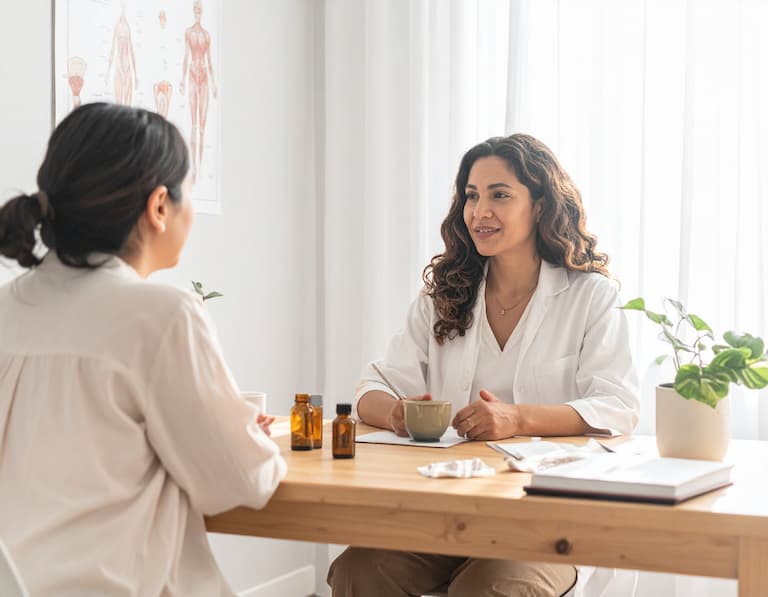 Deux professionnels de santé naturelle échangeant des conseils techniques pendant une séance de réflexologie plantaire