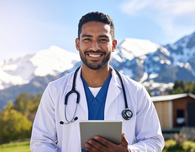 Un professionnel de santé devant un centre médical moderne avec les montagnes des Pyrénées en arrière-plan