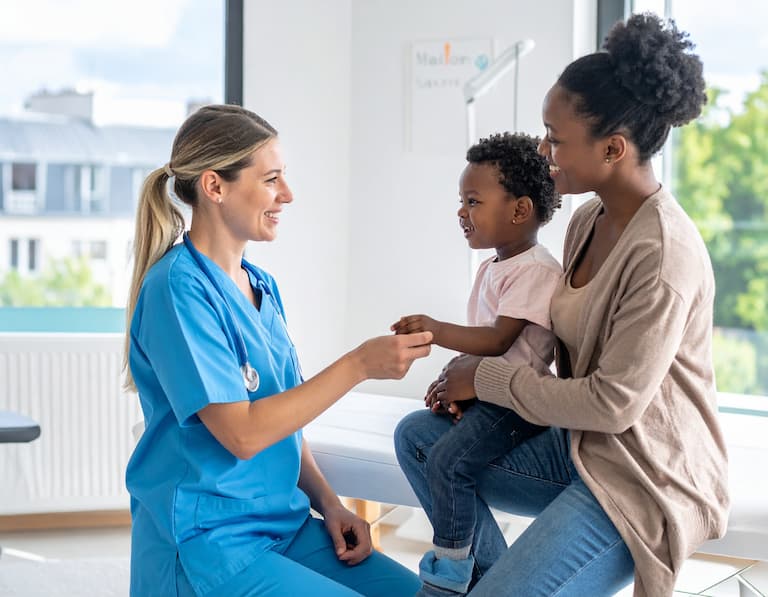 Une femme médecin pédiatre accueillant un enfant et sa mère dans une maison de santé moderne et lumineuse en Île-de-France