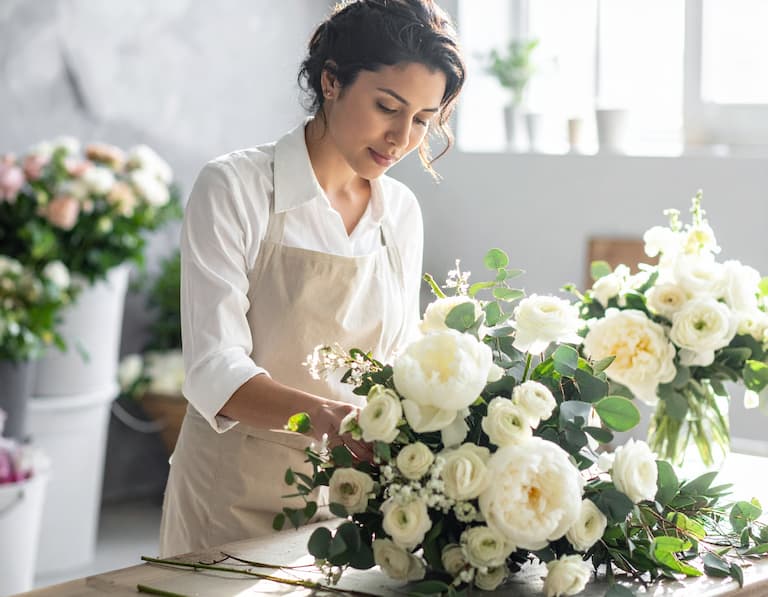 Une fleuriste de mariage composant un centre de table prestigieux dans son atelier baigné de lumière
